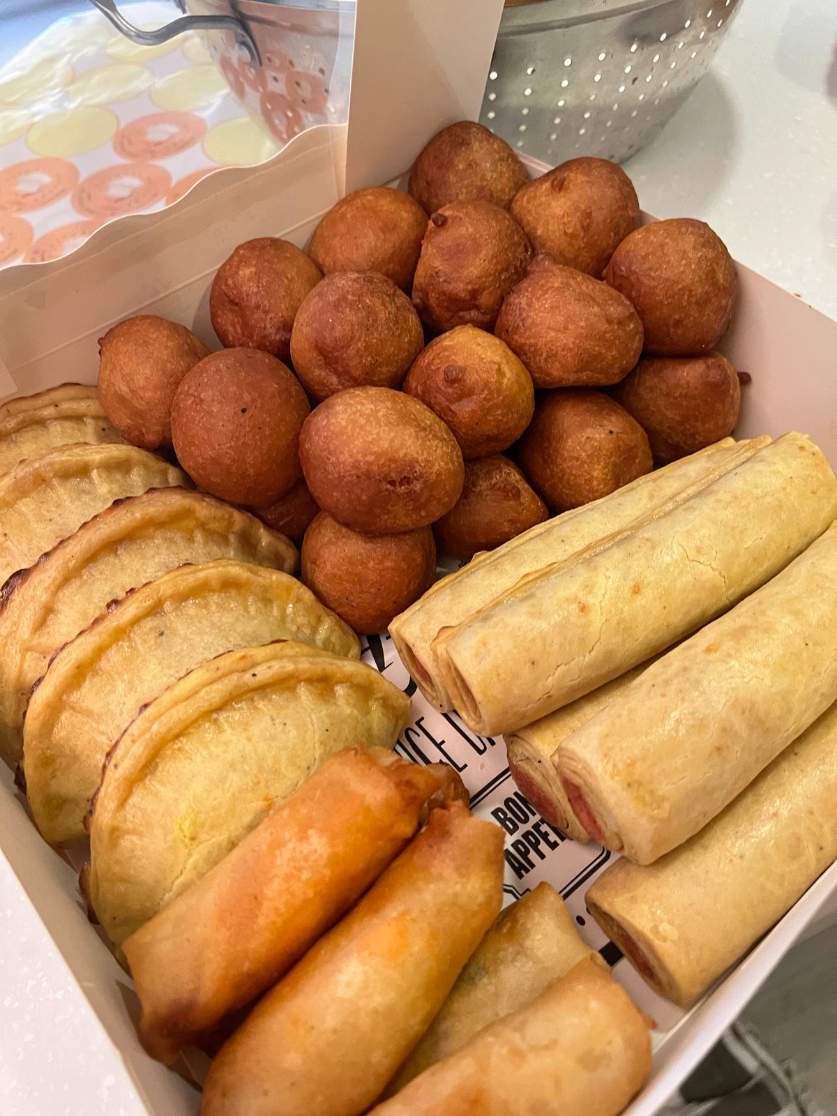 Assorted pastries including cookies, rolls, and donuts in a box.